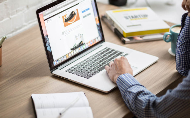 man typing on macbook laptop